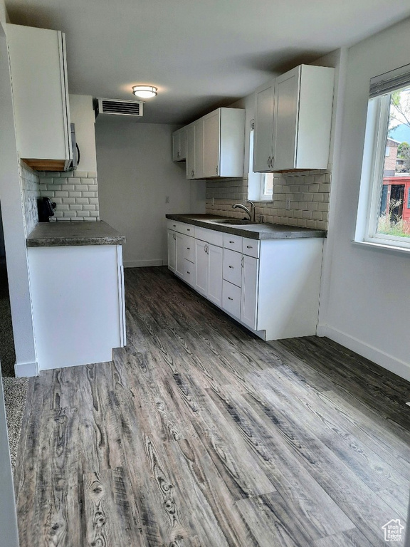 Kitchen featuring backsplash, dark countertops, dark wood finished floors, and white cabinetry