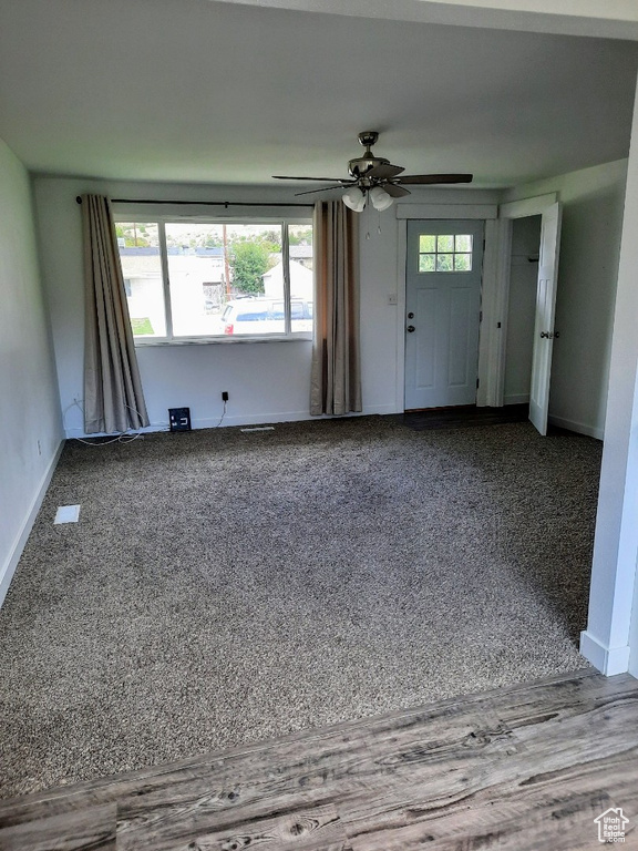 Unfurnished living room with carpet floors and ceiling fan
