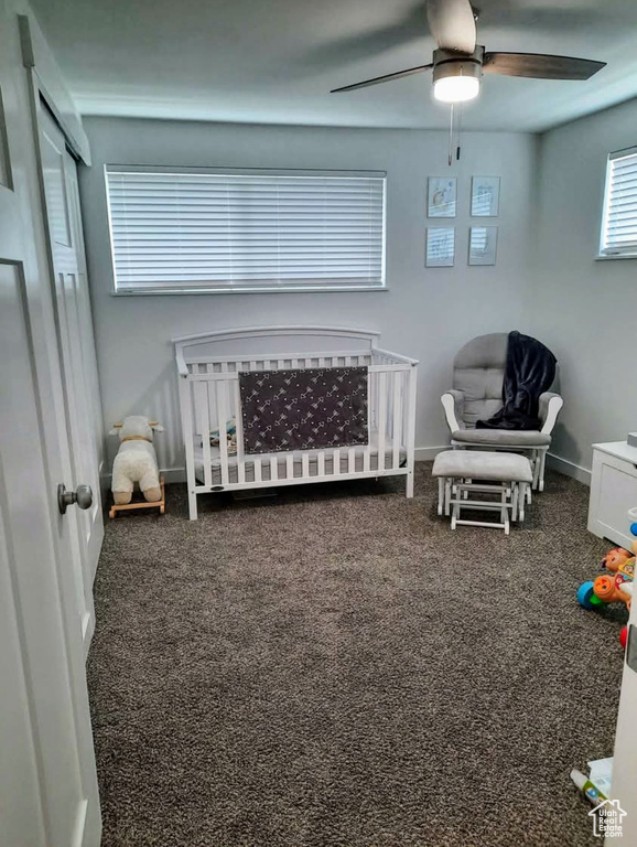 Carpeted bedroom with a crib and a ceiling fan