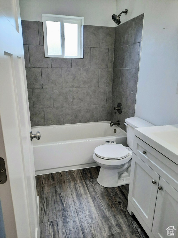 Full bath featuring washtub / shower combination, vanity, and wood finished floors