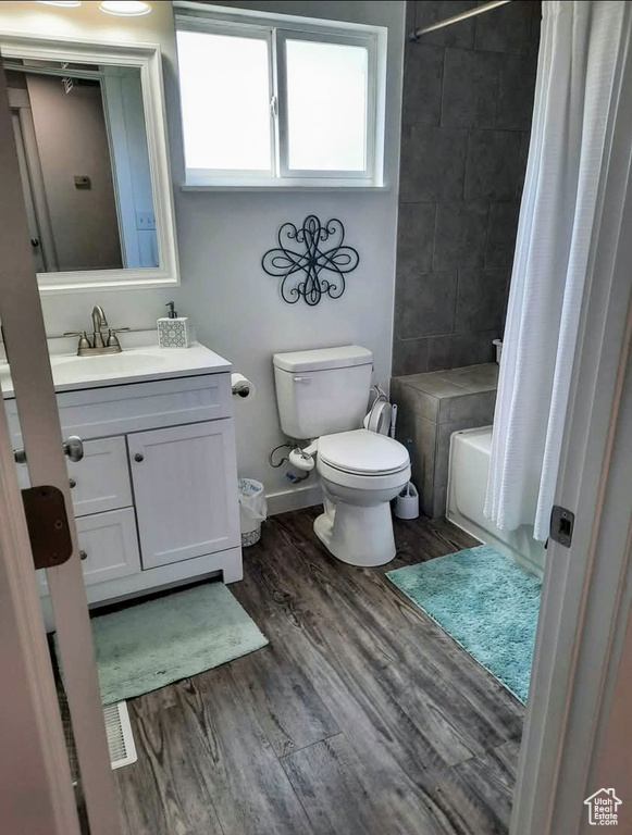 Full bath with vanity, wood finished floors, and shower / bath combination with curtain