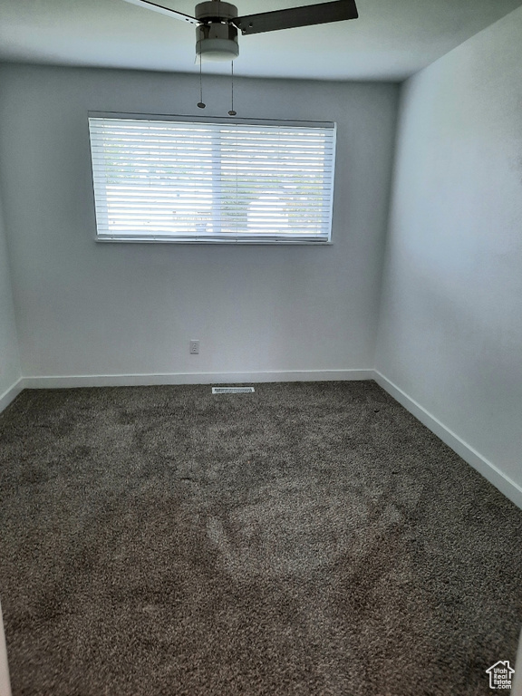 Empty room with plenty of natural light, ceiling fan, and dark carpet