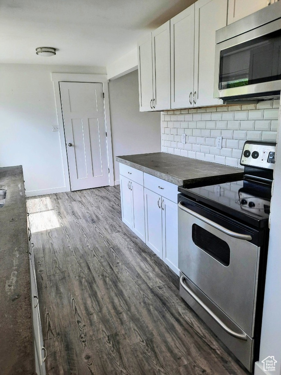Kitchen featuring stainless steel appliances, dark wood-style flooring, white cabinets, and decorative backsplash
