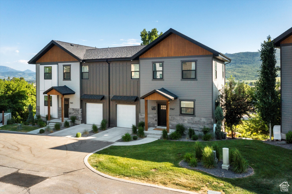 View of front facade featuring concrete driveway, stone siding, and a mountain view