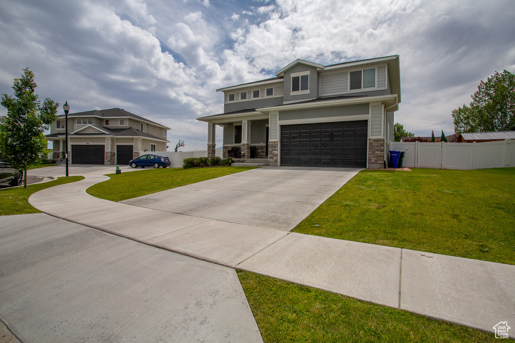 View of front of house with concrete driveway, stone siding, and a garage