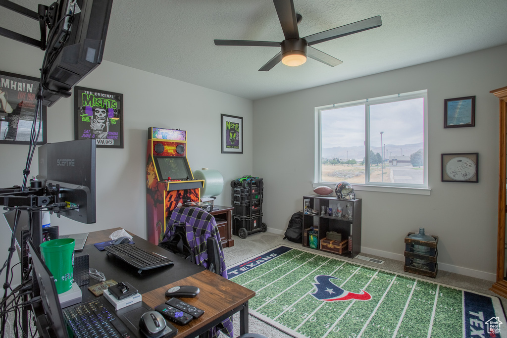 Carpeted home office with a ceiling fan and baseboards