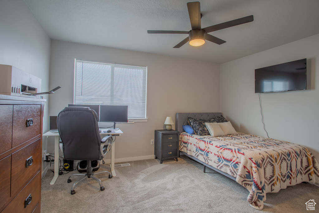 Carpeted bedroom featuring ceiling fan and a desk