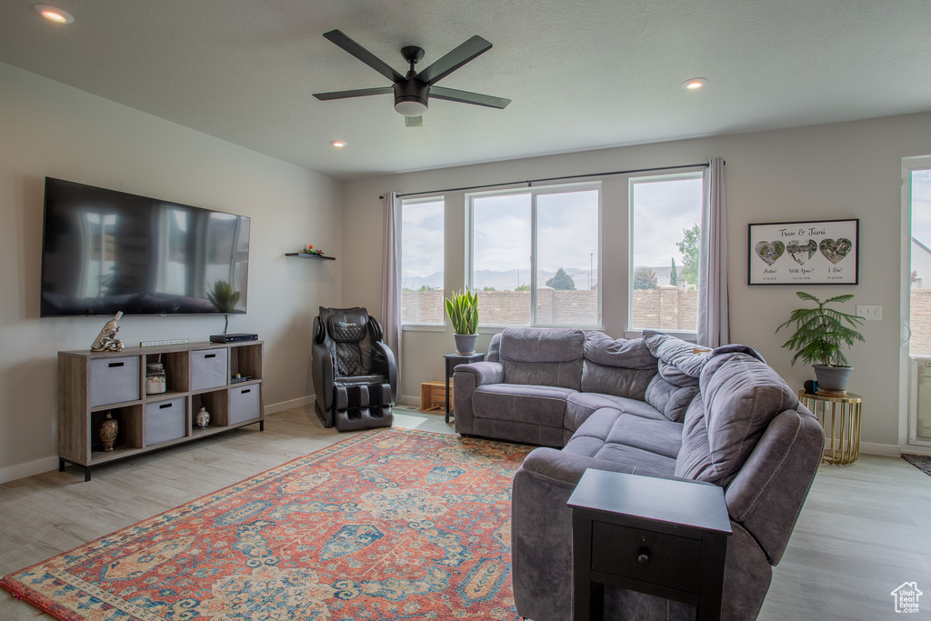 Living room with a ceiling fan, light wood-style floors, and recessed lighting