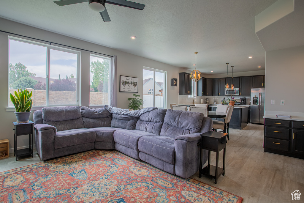 Living room with recessed lighting, a ceiling fan, and light wood-style flooring