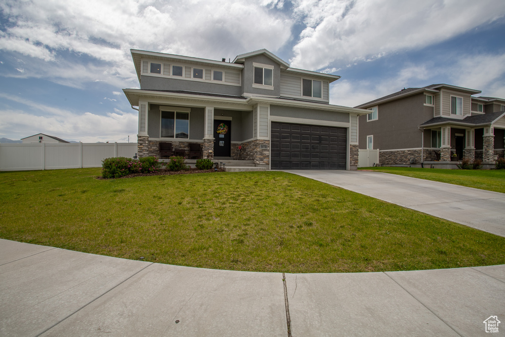 View of front of property featuring covered porch, stone siding, concrete driveway, and an attached garage