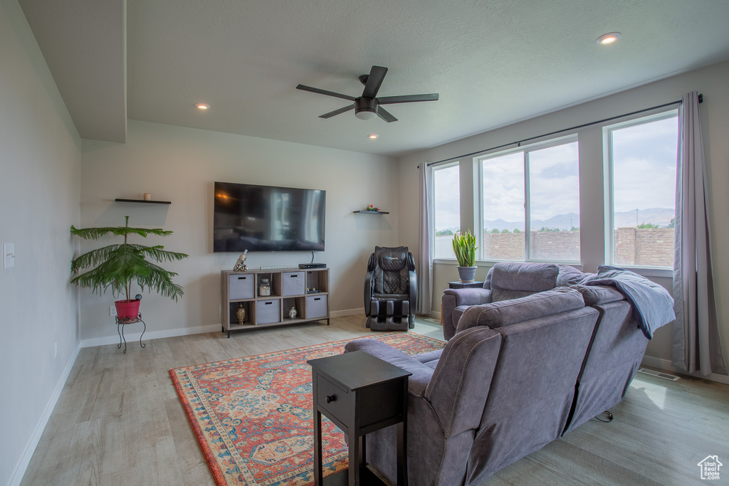 Living room with wood finished floors, ceiling fan, and recessed lighting