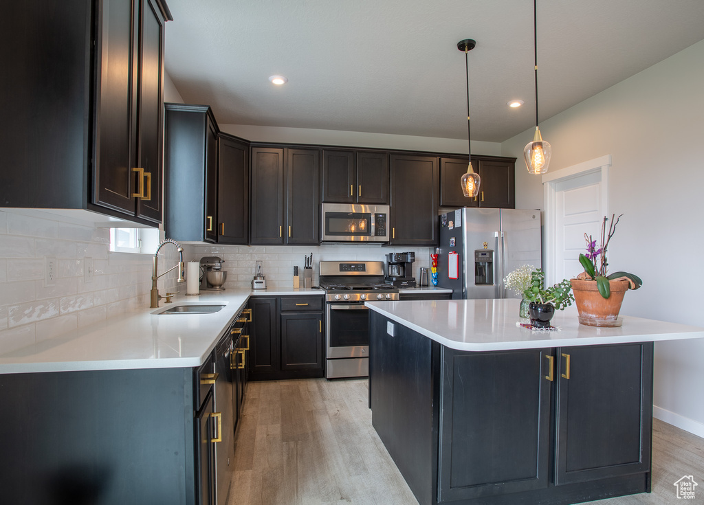 Kitchen with stainless steel appliances, light wood finished floors, decorative backsplash, light countertops, and recessed lighting