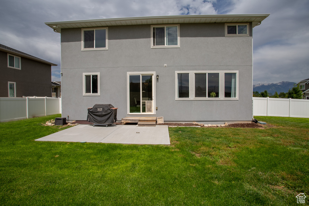 Rear view of house with a fenced backyard, a patio area, stucco siding, and a mountain view