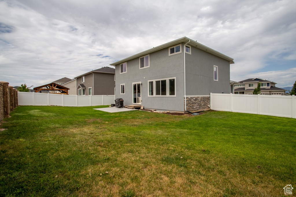 Rear view of property featuring a fenced backyard, a patio, stucco siding, and stone siding