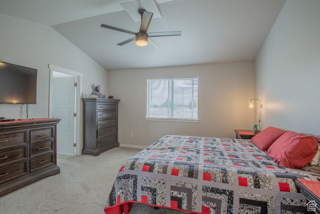 Bedroom featuring light carpet, vaulted ceiling, and a ceiling fan