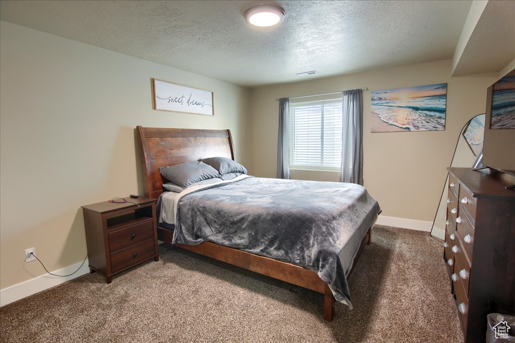 Carpeted bedroom featuring a textured ceiling and baseboards