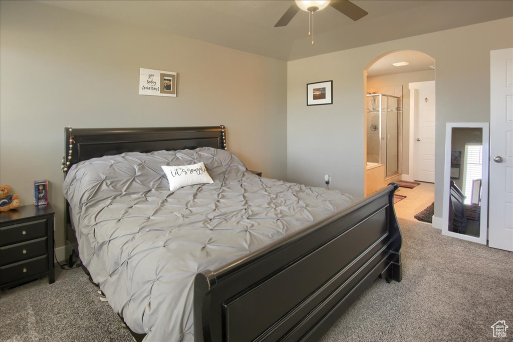 Bedroom featuring carpet flooring, arched walkways, ensuite bathroom, and a ceiling fan