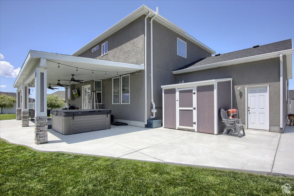 Rear view of house featuring ceiling fan, a patio area, a hot tub, and stucco siding