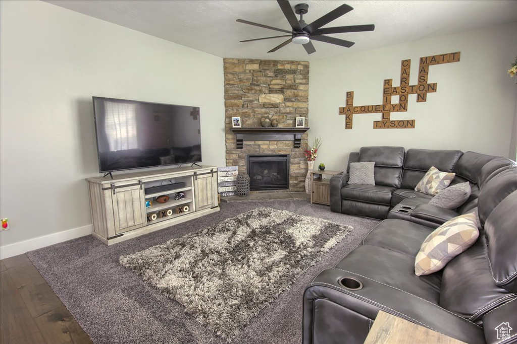 Living room featuring ceiling fan, a fireplace, and wood finished floors