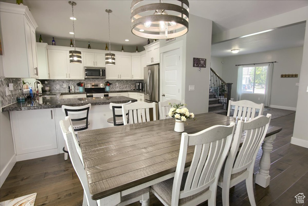 Dining room with stairs, dark wood-style flooring, and recessed lighting