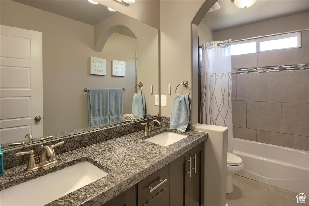 Full bath featuring double vanity, shower / bath combo, and tile patterned floors