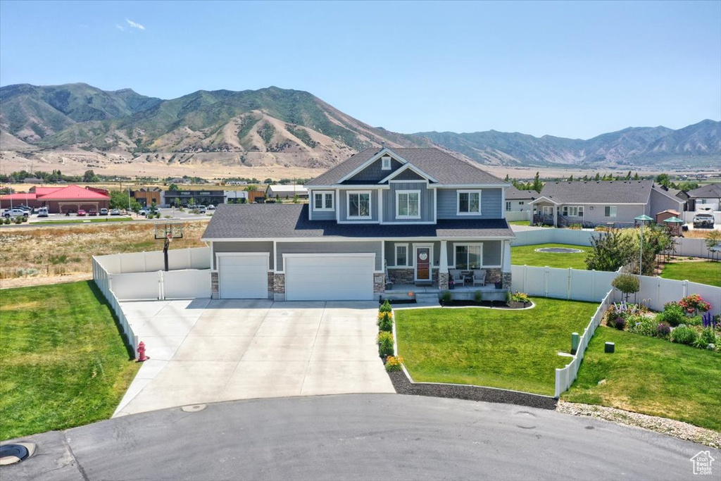 Craftsman house with covered porch, driveway, a mountain view, and stone siding
