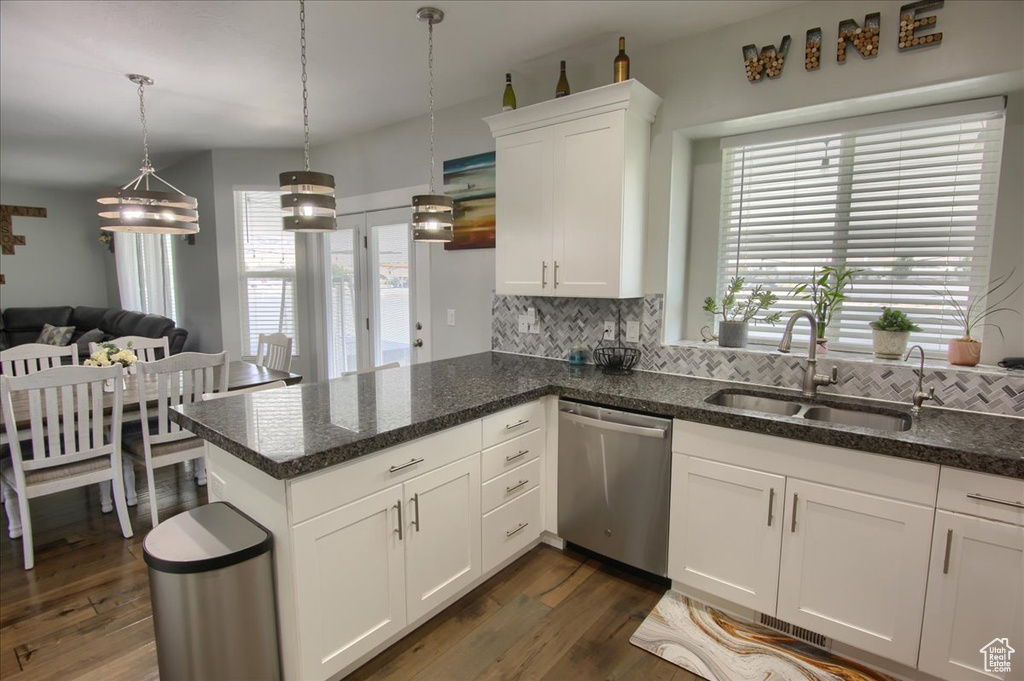 Kitchen with stainless steel dishwasher, backsplash, white cabinetry, and plenty of natural light
