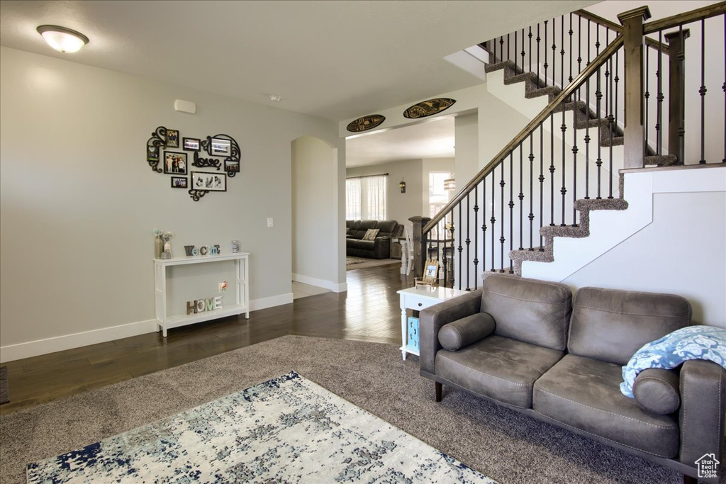 Living area with stairs, wood finished floors, and arched walkways