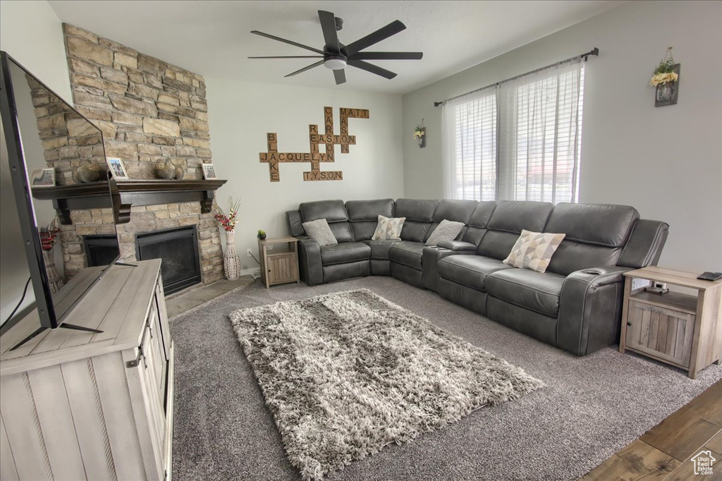 Living area with a ceiling fan, a fireplace, and wood finished floors