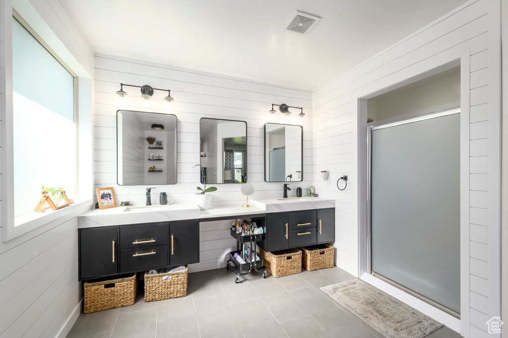 Bathroom featuring double vanity, a shower stall, tile patterned floors, and wood walls