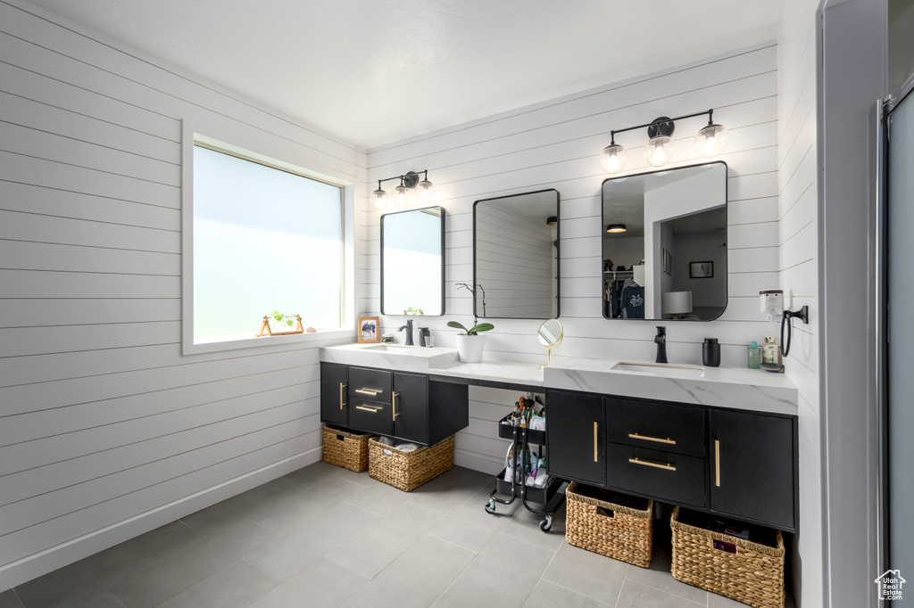 Bathroom with double vanity, wood walls, and tile patterned flooring