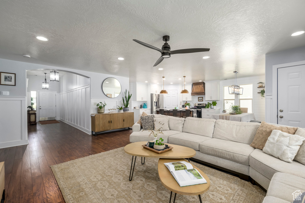 Living area featuring dark wood-style floors, a ceiling fan, recessed lighting, a textured ceiling, and wainscoting