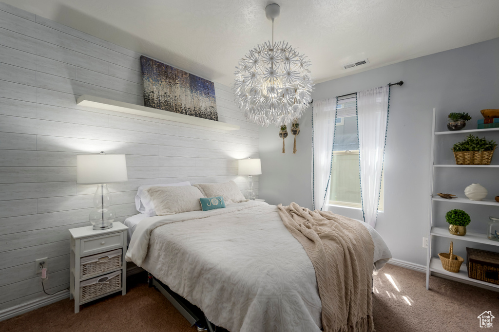 Bedroom featuring dark colored carpet, a chandelier, and wood walls