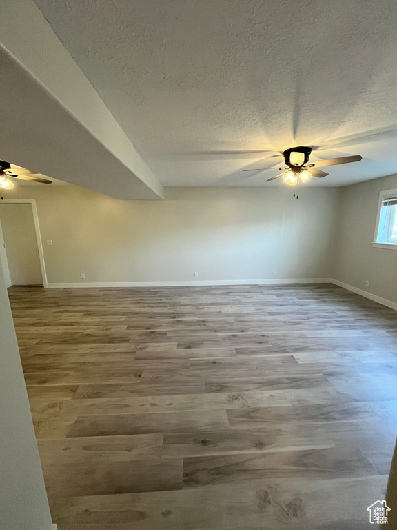 Unfurnished room with ceiling fan, wood finished floors, and a textured ceiling