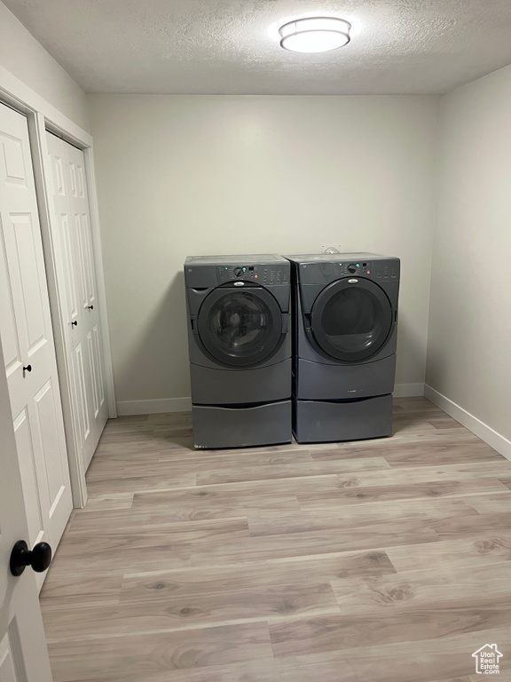 Laundry room featuring washer and clothes dryer, wood finished floors, and a textured ceiling