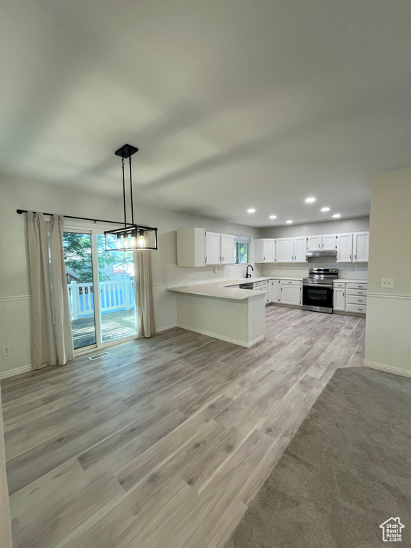 Kitchen featuring stainless steel range with electric cooktop, recessed lighting, a peninsula, light wood finished floors, and healthy amount of natural light
