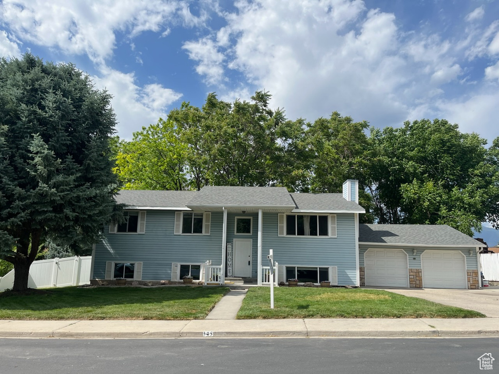 Split foyer home with a garage, concrete driveway, and a chimney
