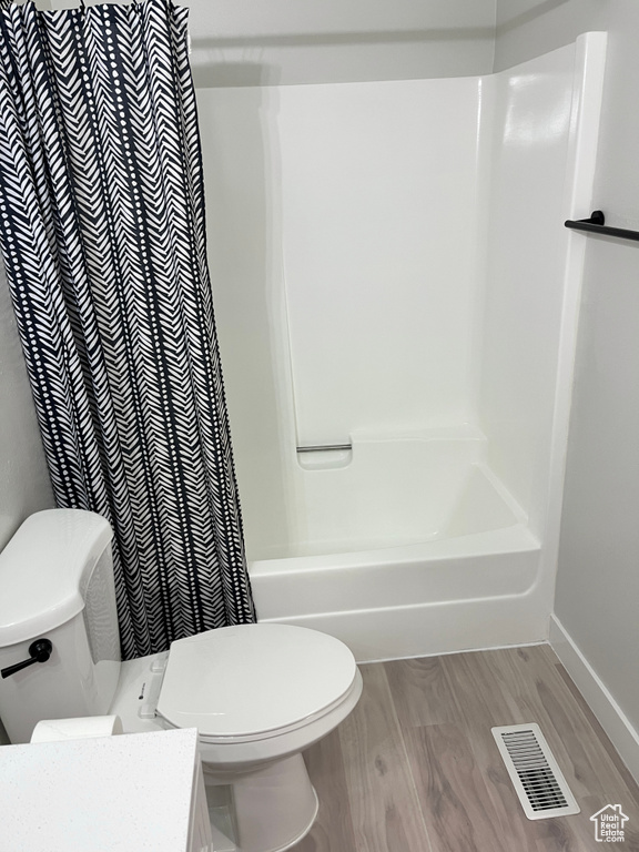 Full bath featuring vanity, wood finished floors, and shower / bath combo with shower curtain