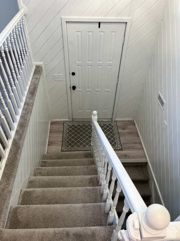 Staircase featuring wooden walls