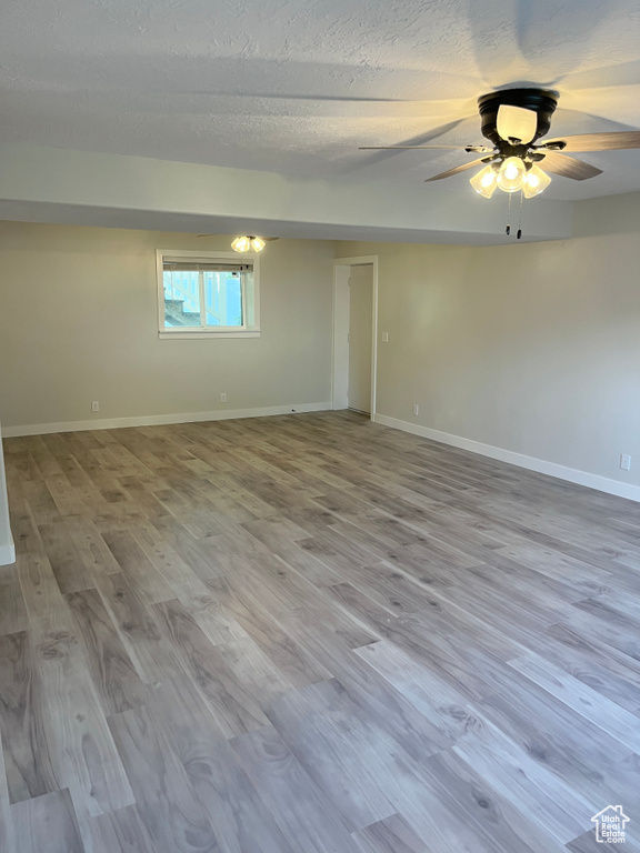 Empty room with wood finished floors, ceiling fan, and a textured ceiling