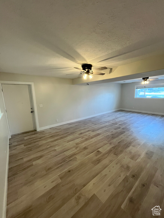 Empty room with wood finished floors, a textured ceiling, and a ceiling fan