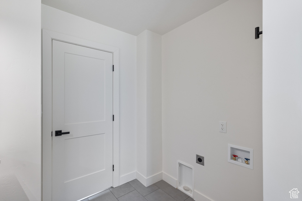 Laundry area with electric dryer hookup, hookup for a washing machine, and tile patterned floors