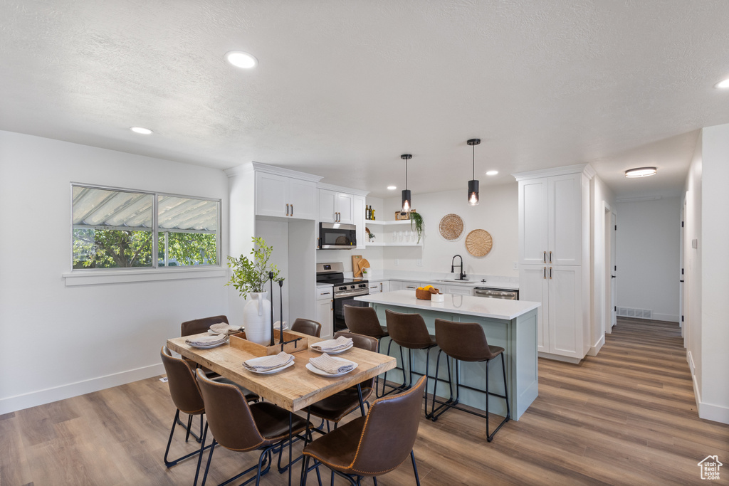 Dining space featuring wood finished floors, recessed lighting, and a textured ceiling