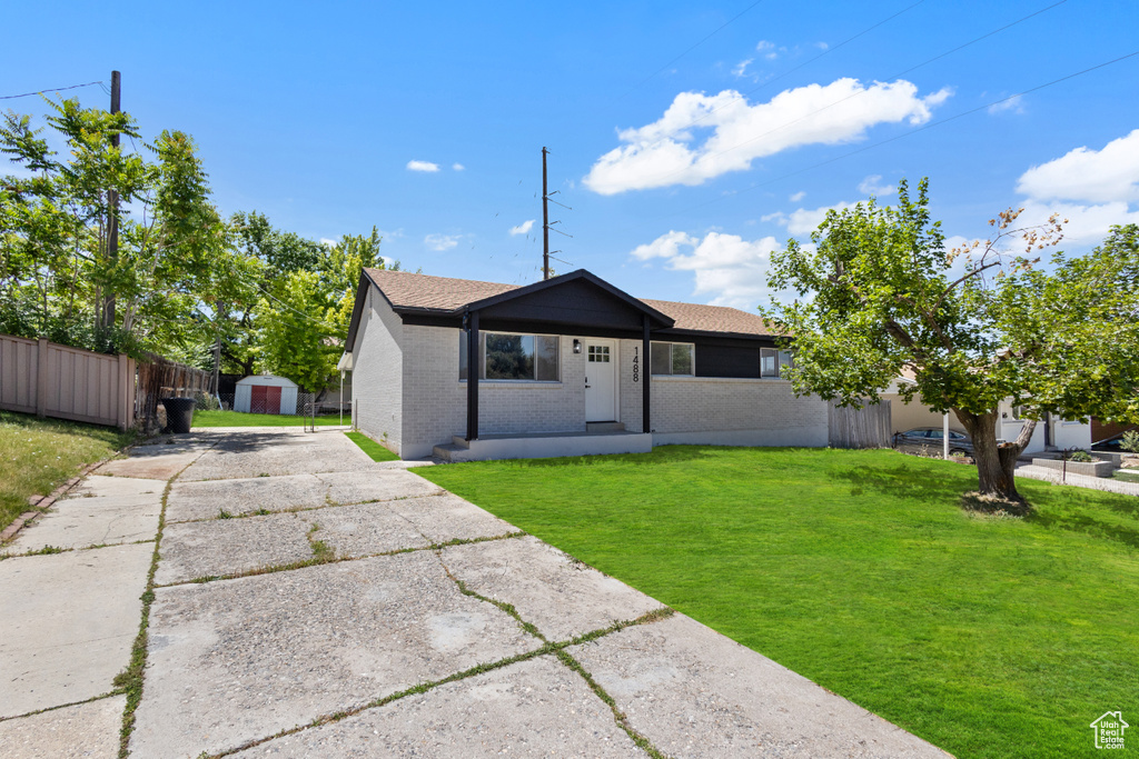 View of front of property with a shed, brick siding, driveway, and roof with shingles