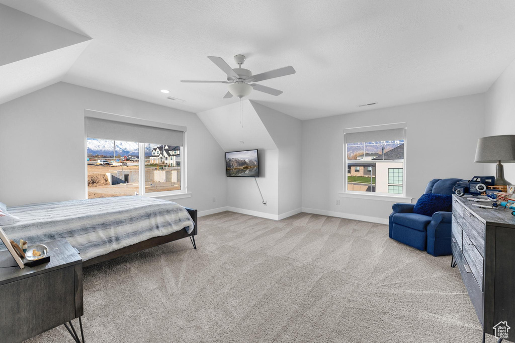 Bedroom featuring light colored carpet, lofted ceiling, and a ceiling fan