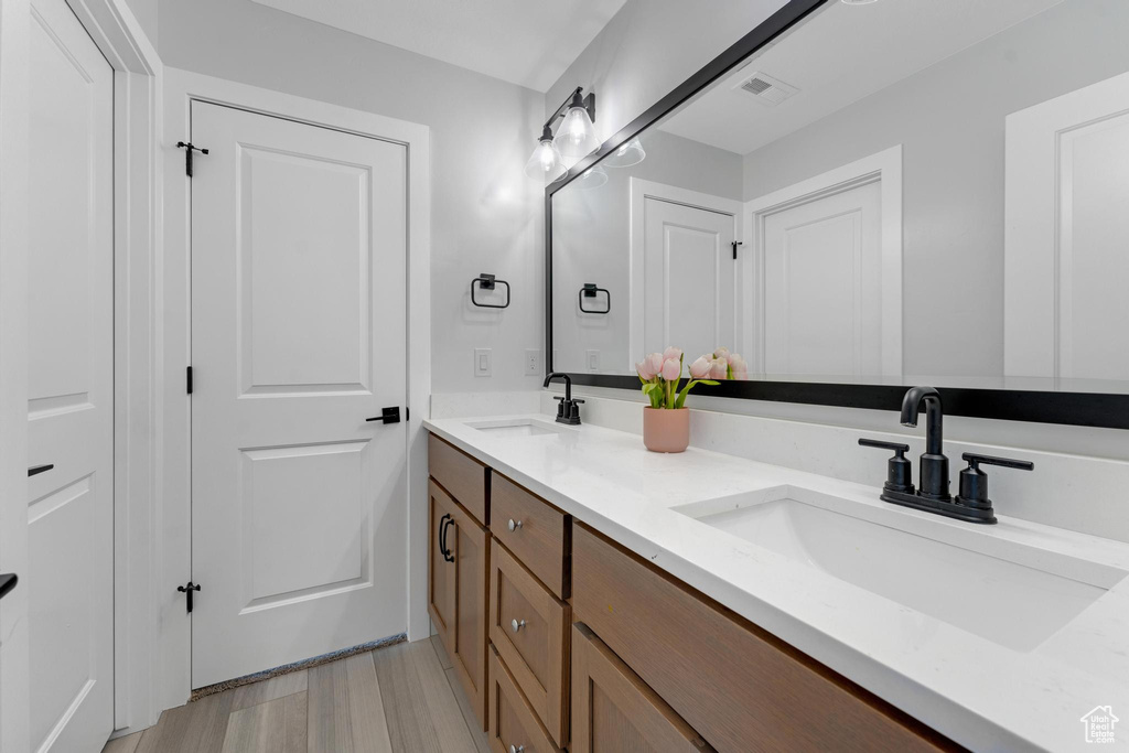 Full bathroom with double vanity and wood finished floors