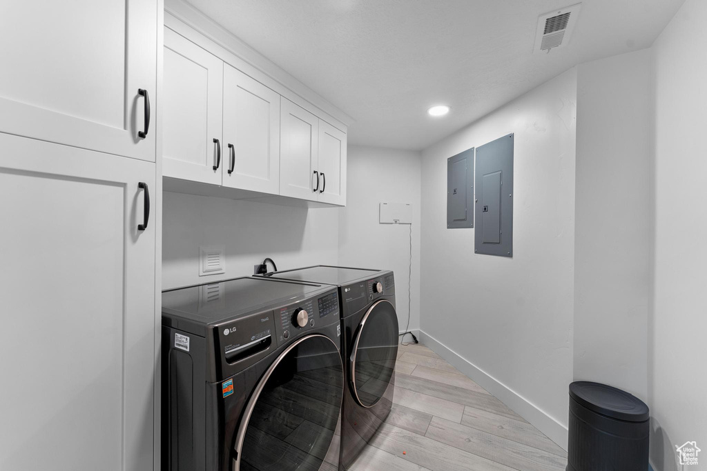 Washroom with cabinet space, washer and dryer, electric panel, light wood finished floors, and recessed lighting