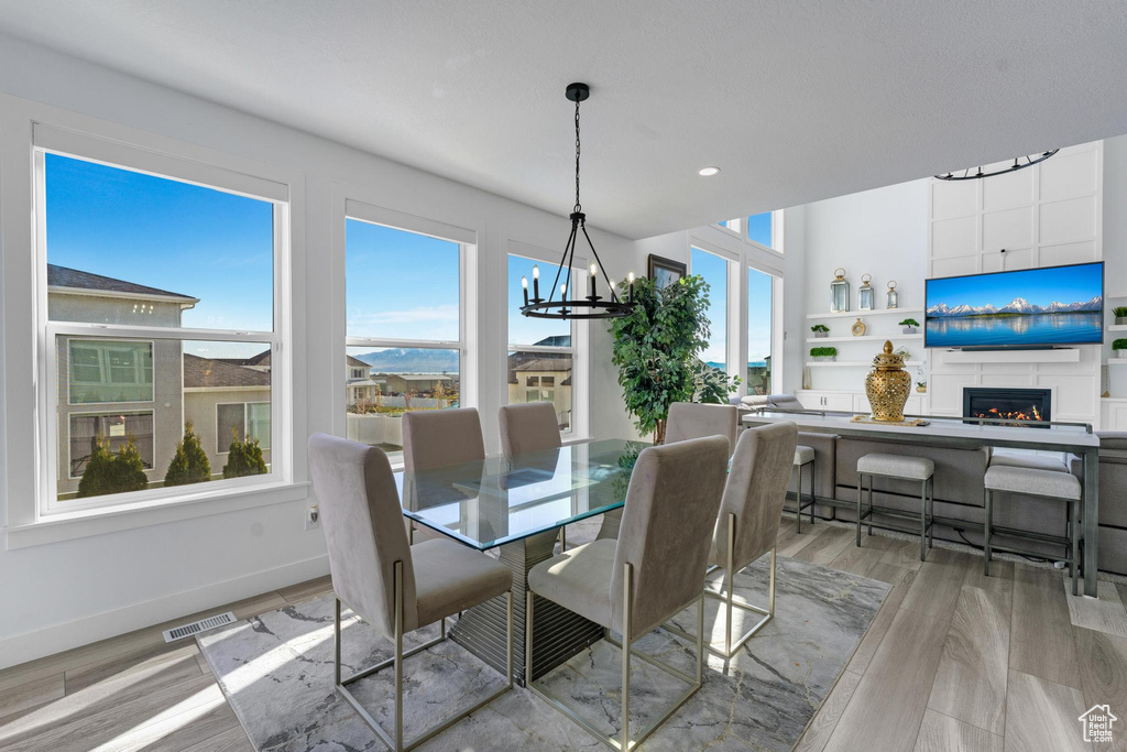 Dining area featuring a chandelier, plenty of natural light, a fireplace, light wood finished floors, and recessed lighting