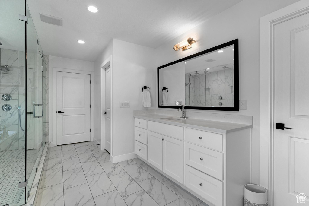 Bathroom featuring recessed lighting, marble finish floors, a marble finish shower, and vanity