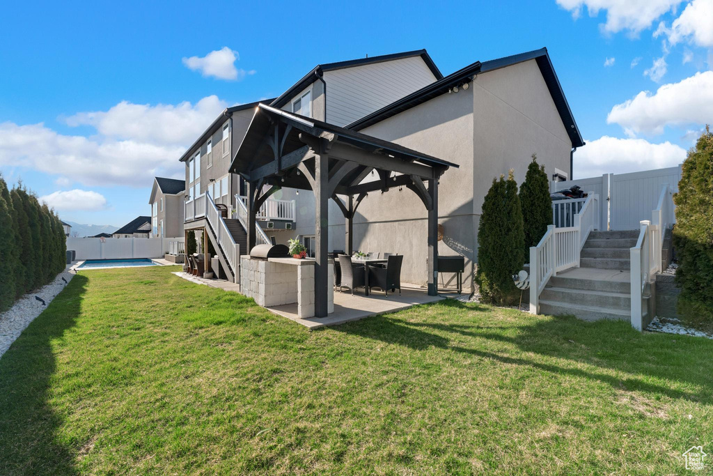 Back of house with stairs, a gazebo, a fenced backyard, a patio area, and stucco siding